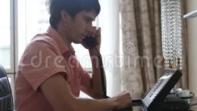 年轻人坐在豪华的酒店房间里，拿起电话给酒店打电话。